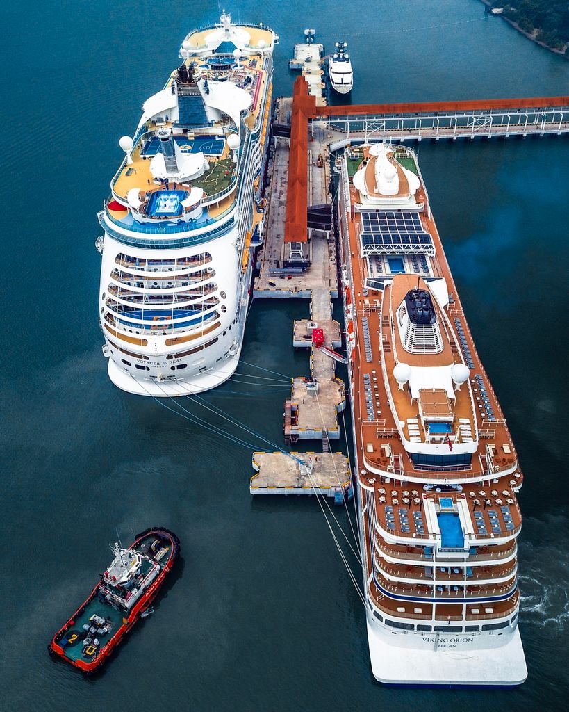 Aerial shot of two cruise ships docked at a port in Klang, Malaysia, with a small tugboat nearby.