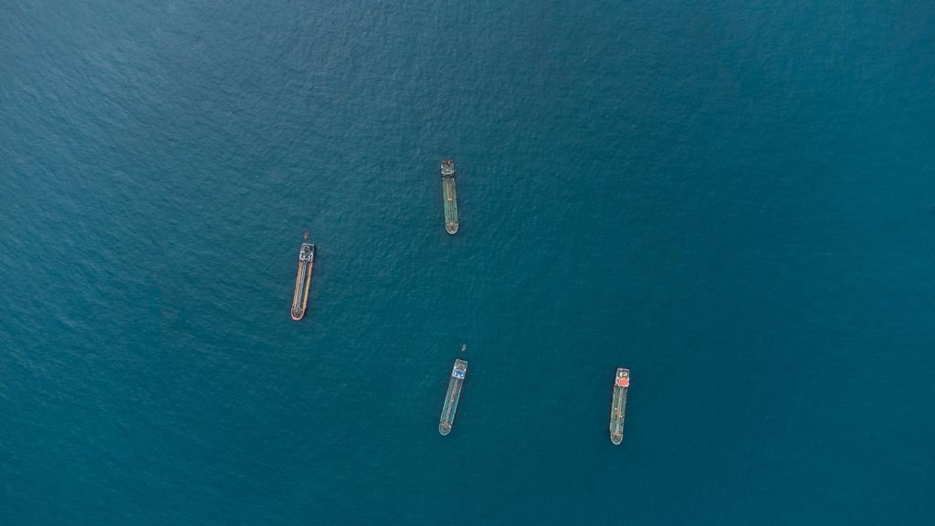 Top-down view of four cargo ships on vast ocean, showcasing maritime transport.
